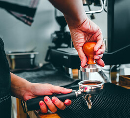 Close-up of hand Barista cafe making coffee with manual presses ground coffee using a tamper at the coffee shop