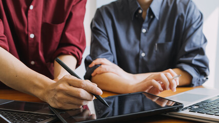 Asian colleagues man and woman discussing and working with laptop computer on office desk in the office