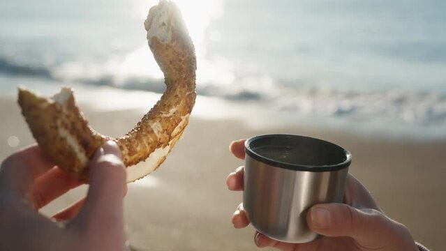 A metal mug from a thermos and hot tea with a bagel, steam is coming. Cool morning at the sea.