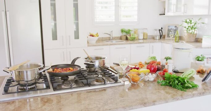 General view of kitchen and frying pan with vegetables on table