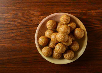 Til Laddu served in a bowl on wooden background, shot from above. Nutritious and healthy Indian traditional sweet.