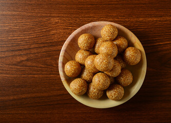 Til Laddu served in a bowl on wooden background, shot from above. Nutritious and healthy Indian...