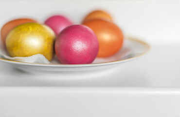 Orange, pink and gold Easter eggs on a plate.