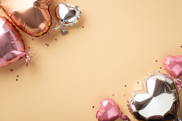 Valentine's Day concept. Top view photo of heart shaped metallic balloons and shiny confetti on isolated pastel beige background with copyspace