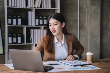 business woman sitting at her desk, reading stats and graphs on paperwork at the office.