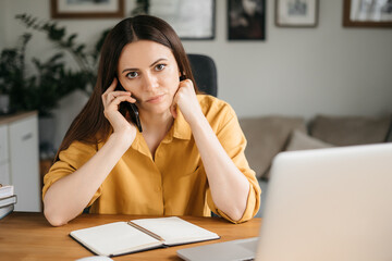 Bored tired woman using laptop for remote work, sitting in living room, student or freelancer...