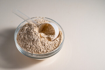 Protein powder in a bowl and scoop. Food supplement sport nutrition. Copy space
