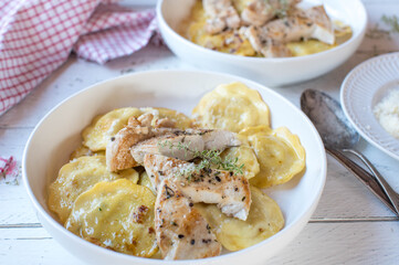 Chicken breast with pan fried ravioli with mushroom filling. Served on plates on white wooden background