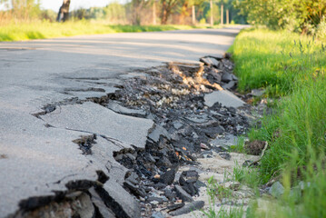 Destroyed edge of asphalt pavement in the countryside. Destruction of road caused by flood water