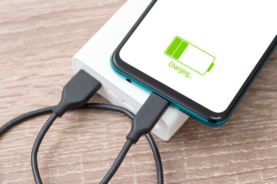 Close up of mobile phone charging from power bank. Using powerbank to charge smartphone