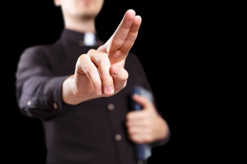 Priest making a blessing gesture, isolated on black background