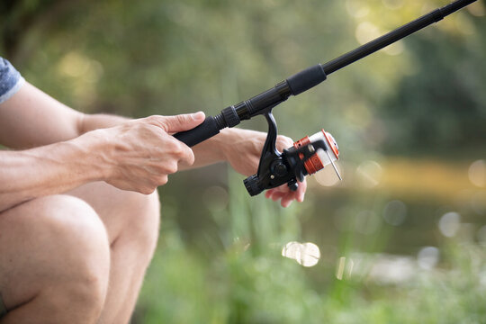 man holds fly rod with one hand