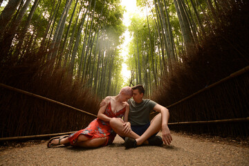 Couple sit in bamboo forest with heads together