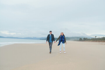 Couple walking on beach smiling on dreary day