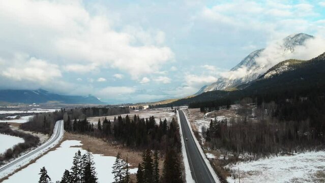 Winter Landscape in British Columbia, Canada with Car Driving Along Cariboo Highway 95 and Cloudy Mountains in the Background