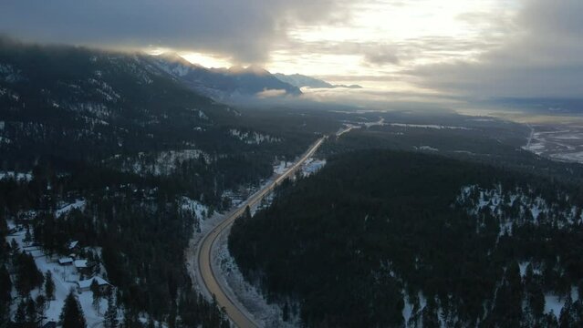Panoramic View of Cariboo Highway 95 Running into the Horizon Surrounded by Impressive Mountains Range Covered in Clouds During Sunrise Warm Light: warm light , spectacular aerial approach shot