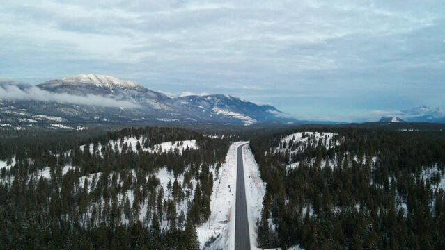Aerial View of Cariboo Highway 95 Running into the Horizon Surrounded by Impressive Snow Covered Mountains and Forests on a Cloudy Day During Blue Hour: Panoramic Scene