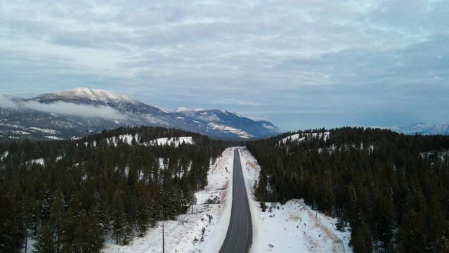 Cloudy Blue Hour Aerial View of Cariboo Highway 95 Running into the Horizon Surrounded by Impressive Snow Covered Mountains and Forests: Panoramic Scene