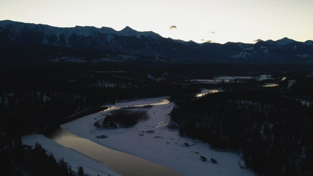Winter Landscape at Golden Hour: Aerial Panning Right Shot of Glowing River and Grand Mountains in British Columbia, Canada
