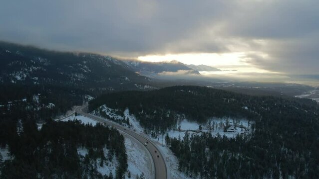 Sunrise Warm Light Illumines Cariboo Highway 95 Surrounded by Majestic Cloud-Covered Mountains: Stunning Aerial reveal Shot with Panoramic View