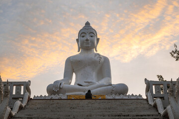 One person meditating in front of the big white Buddha statue in the early morning
