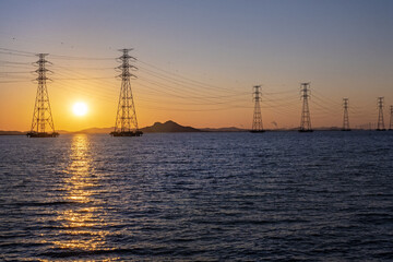 바다 위 설치된 송전탑과 그 뒤로 지는 태양