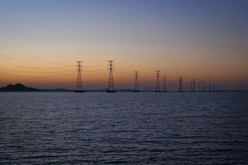 해지는 저녁 노을과 바다 위에 설치된 송전탑