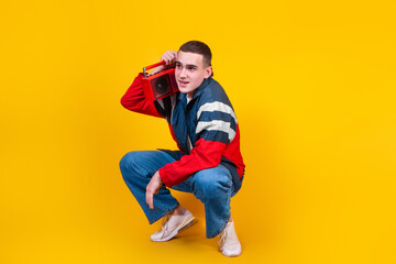 Fototapeta premium A handsome guy in the style of the 90s with a boombox on a yellow background