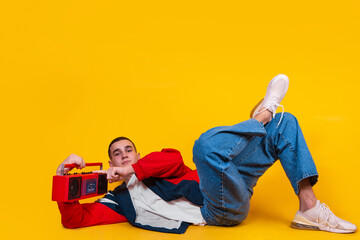 A handsome guy in the style of the 90s with a boombox on a yellow background