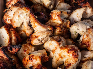 Macro of meat on metal skewers - juicy chicken grilling on fire, coals and smoke in grill. Macro of herbed and seasoned cubes of meat. Grilling meat