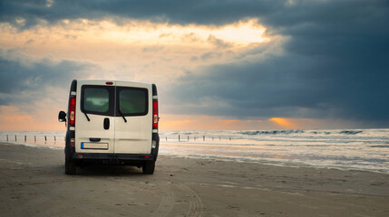 Camper van driving next to the wadden sea at low tide, traveling at the beach of Romo in Denmark,...