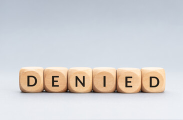 Denied word on wooden blocks on gray background. Copy space