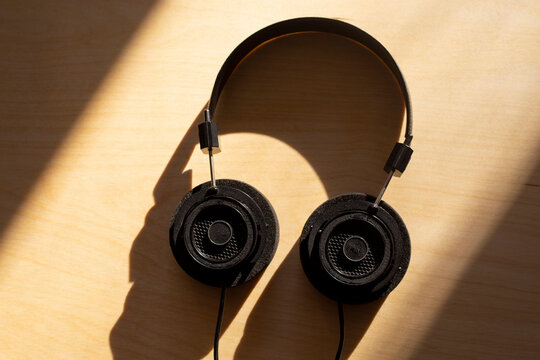Black large headphones for comfortable listening to music and podcasts on a wooden background. Background for a list of music on a sunny autumn day. Listen to podcasts
