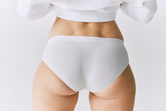 Cropped image of female body, buttocks in underwear posing over grey studio background. Back view. Anti cellulite care