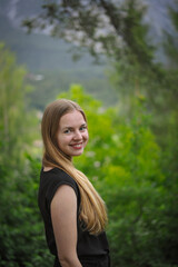Naklejka premium charming charming cute smiling girl with an open, honest face against a forest in a soft light