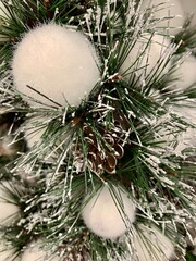 Snow-covered branch with a cone and fluffy white balls. Festive mood. New Year's decor 
