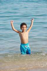 Happy child playing in the sea. Kid having fun outdoors. Summer vacation and healthy lifestyle concept. 