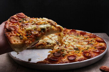 Pizza slices topped with melted cheese and other topping variants are picked up by hand.