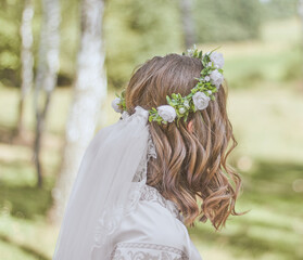 Wedding jewelry on girl head. Green wreath with white flowers holding a veil. Wedding style of bride. Beautiful hair. Beautiful natural background.