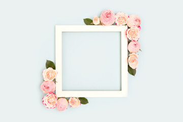 Square frame made of pink rose flowers on a blue background. Place for text.