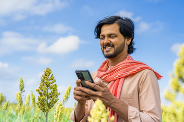 happy farmer using mobile phone at corn field - concept of technology, connection and modern...