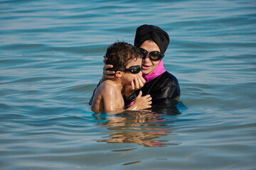 Mother teaching her son how to swim at the sea. child playing with his mother at sea
