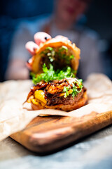 Chefs woman hand open burger with beaf and vegetables