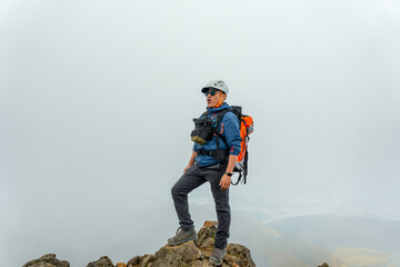 man hiker with backpack in front of a mountain