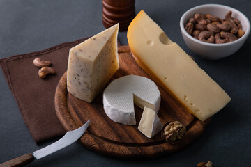 various types of cheese with nuts and knife on rustic wooden table