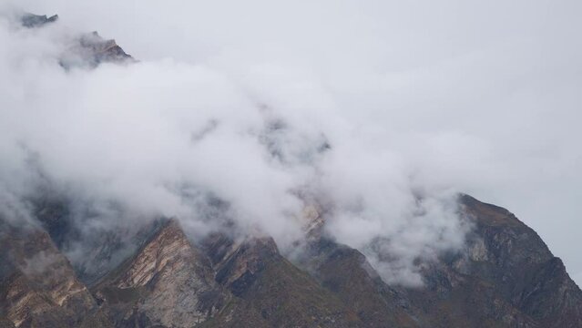 4K shot of fog around the mountain peaks during the stormy weather at Tandi in Lahaul Spiti district at Himachal Pradesh, India. Clouds rolling over the peaks of the mountain. Nature background. 
