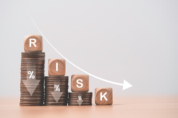 Risk wording on decreasing coins stacking with down arrow for financial banking risk analysis and...