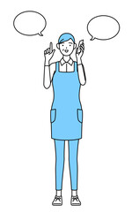 電話をしながら指さしをするエプロンを着たシニア女性