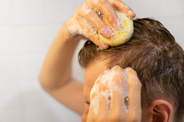 A man uses a solid shampoo bar in the bathroom. Sustainable hair care. An applying shampoo to the...