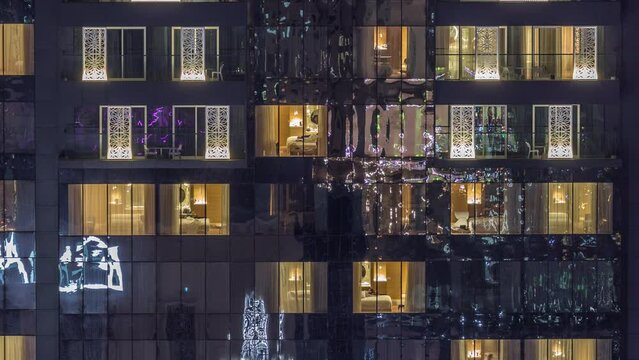 Windows lights in modern towers and residential buildings timelapse at night. Multi-level skyscrapers with illuminated rooms inside